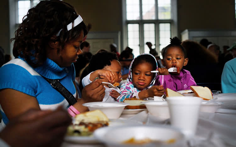 Mother and children at a foodbank eating a meal.